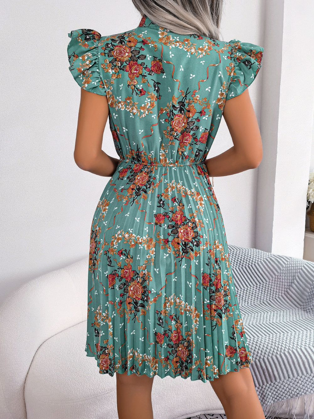 Turquoise floral mini dress with ruffle sleeves and pleated skirt.