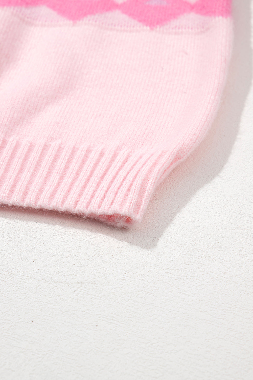 Pink acrylic knit sweater with diamond pattern and ribbed hem detail.