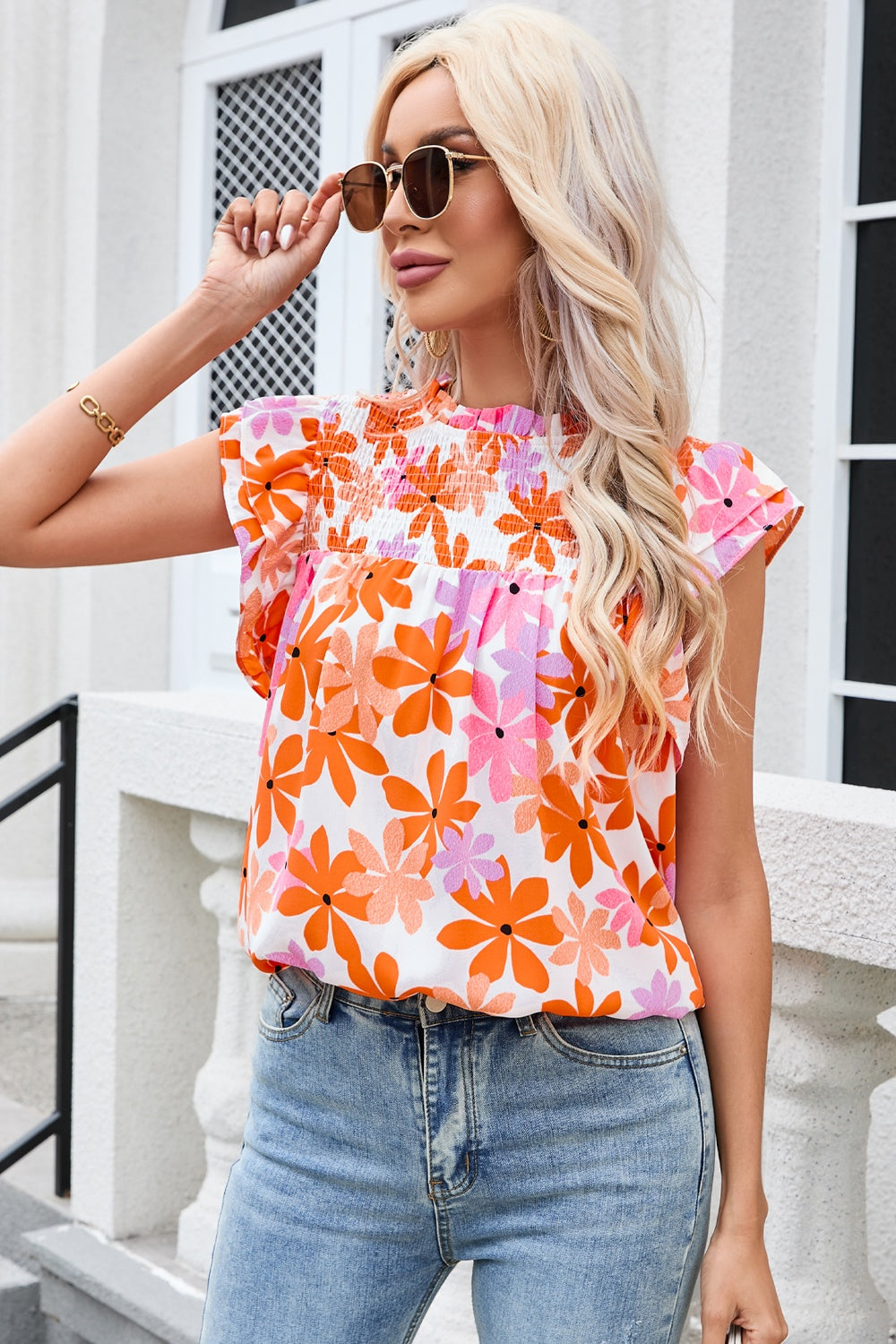 Multicolor floral smocked bodice flutter sleeve blouse with a high neckline.