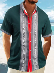 Men's dark green short sleeve shirt with bold geometric print panels and red trim.