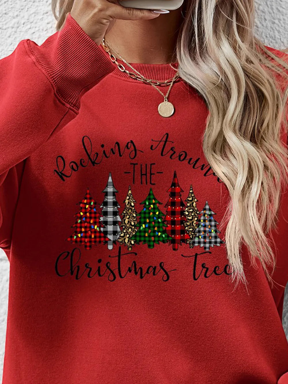 Red crewneck sweatshirt with a graphic of assorted Christmas trees and text.