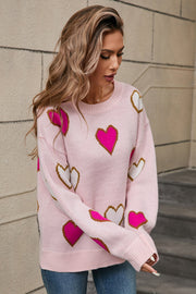 Pink knit crewneck sweater with allover heart motif in white and fuchsia.
