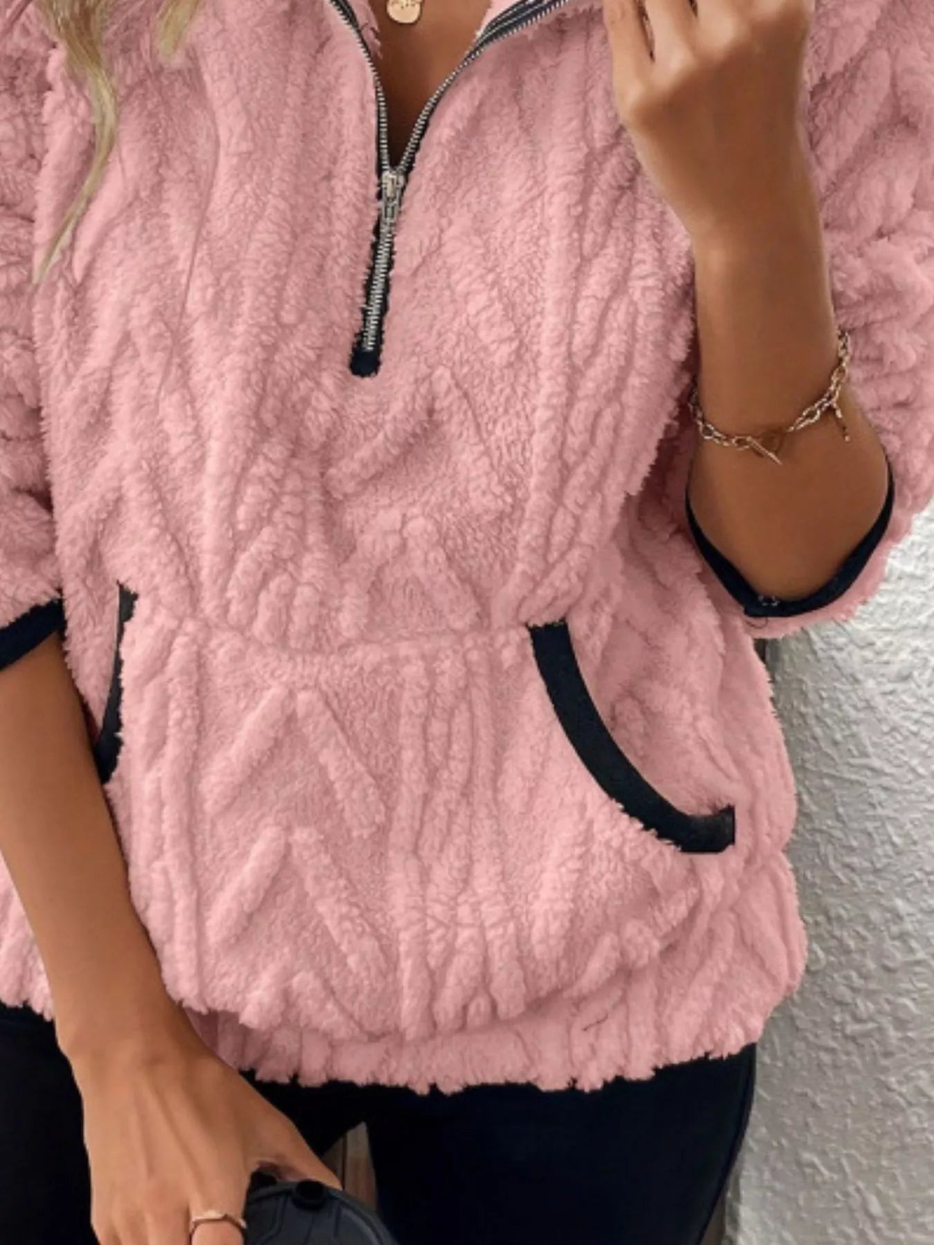 Pink sherpa half zip sweatshirt with textured pattern and black trim pockets.