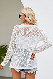 White openwork knit tunic with chevron pattern and long sleeves, styled with denim shorts.