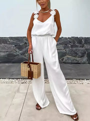 White wide-leg jumpsuit with floral applique straps and blouson waist.