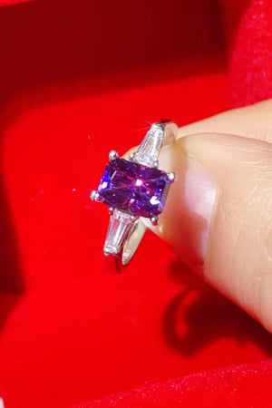Emerald-cut purple moissanite and baguette platinum ring with accent stones.