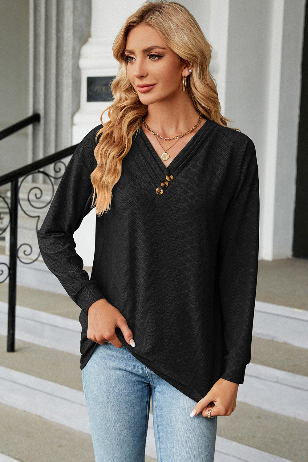 Black textured henley v-neck top with button detail and long sleeves.
