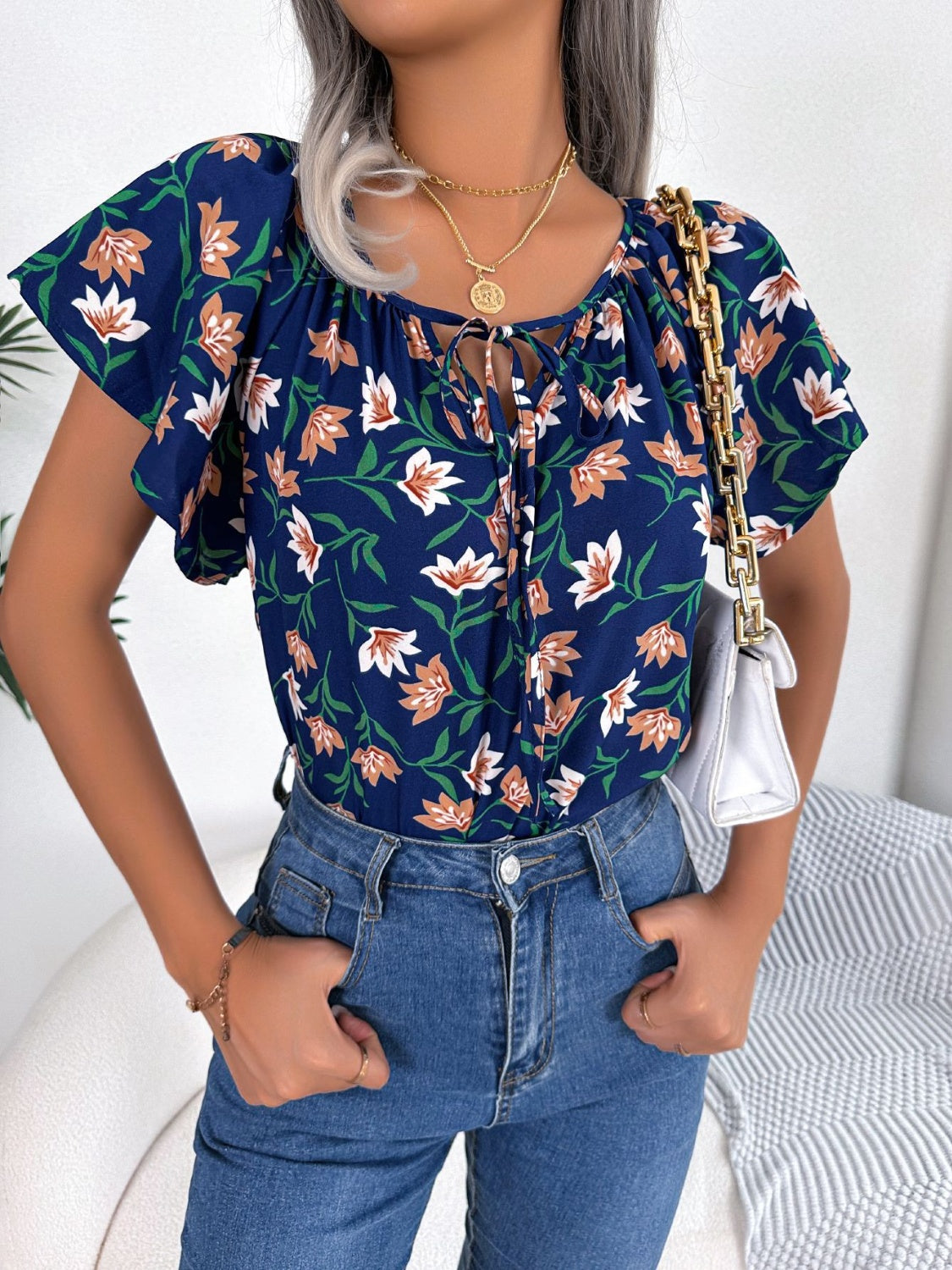 Dark blue floral ruffle sleeve tie-neck blouse with white and orange flowers.