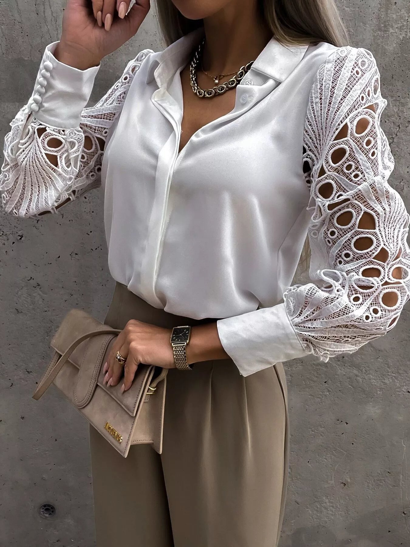 White collared blouse with intricate lace sleeves and buttoned cuffs.
