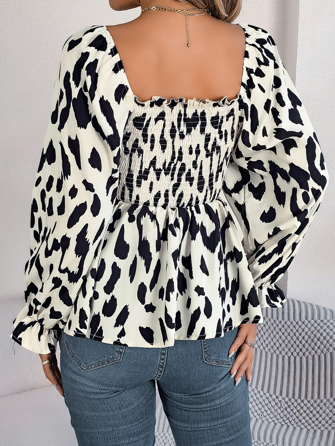 Smocked bodice square neck blouse in black and cream animal print with long sleeves.