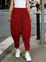 Burgundy harem pants with pockets and vertical pinstripes, styled with white sneakers.