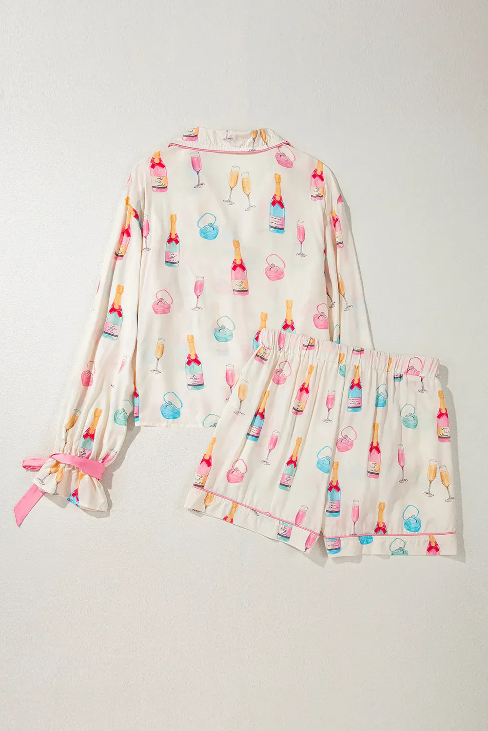 Champagne print silk pajama set in white with pink trim and bow details on sleeves.