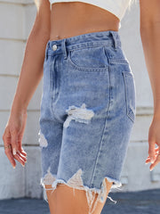 Distressed denim bermuda shorts in medium wash with frayed hem and ripped details.
