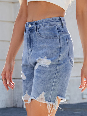 Distressed denim bermuda shorts in medium wash with frayed hem and ripped details.