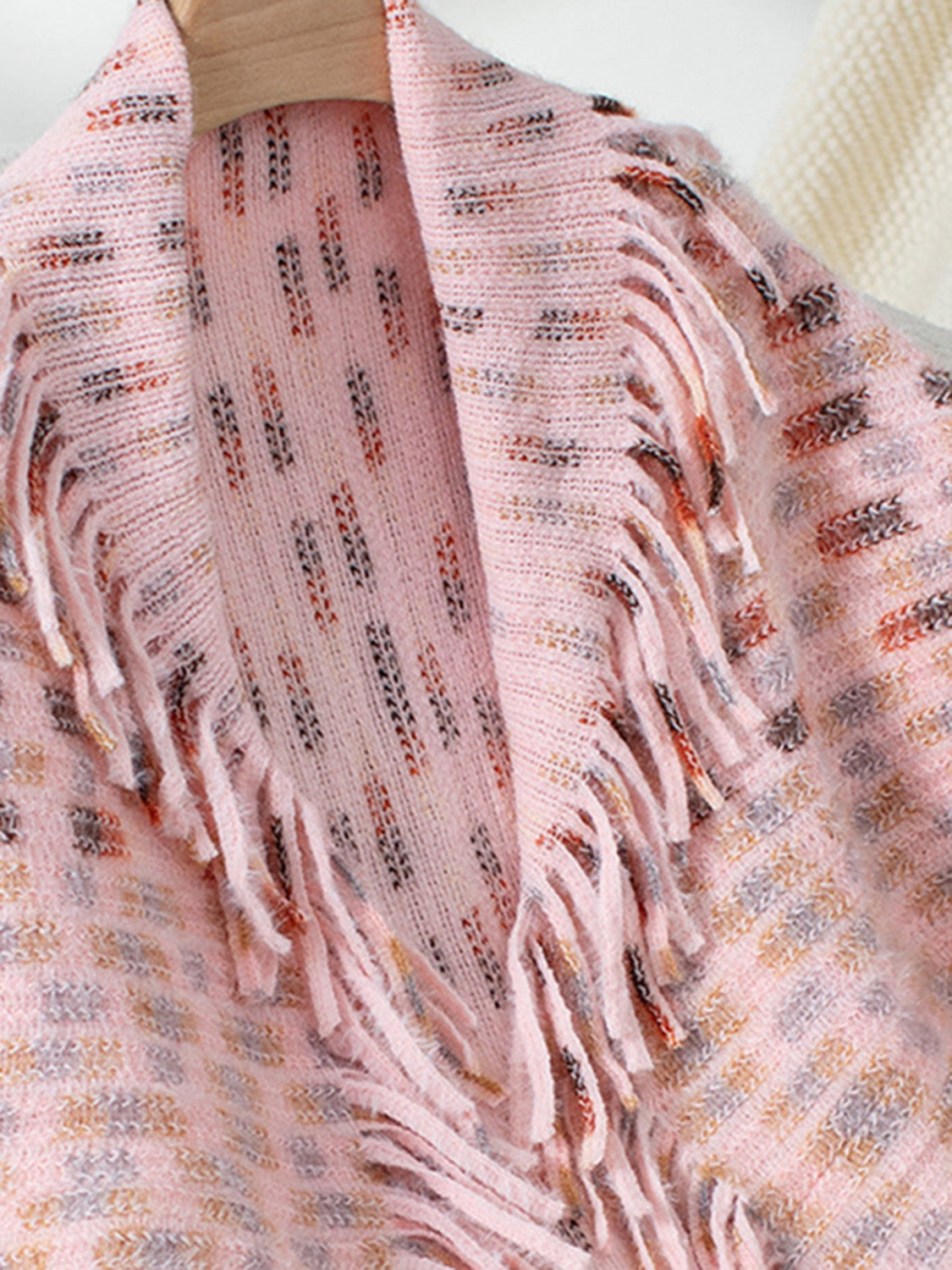 Textured fringe shawl cardigan in blush pink with a patterned knit and fringe detail.