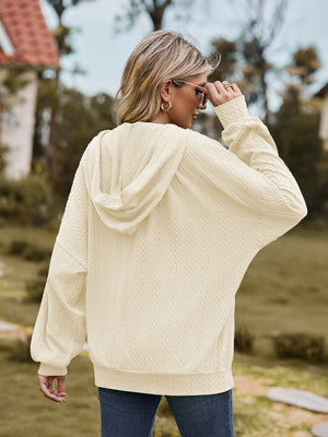Pale blush textured knit dolman sleeve hoodie with a hood and cuffed sleeves.