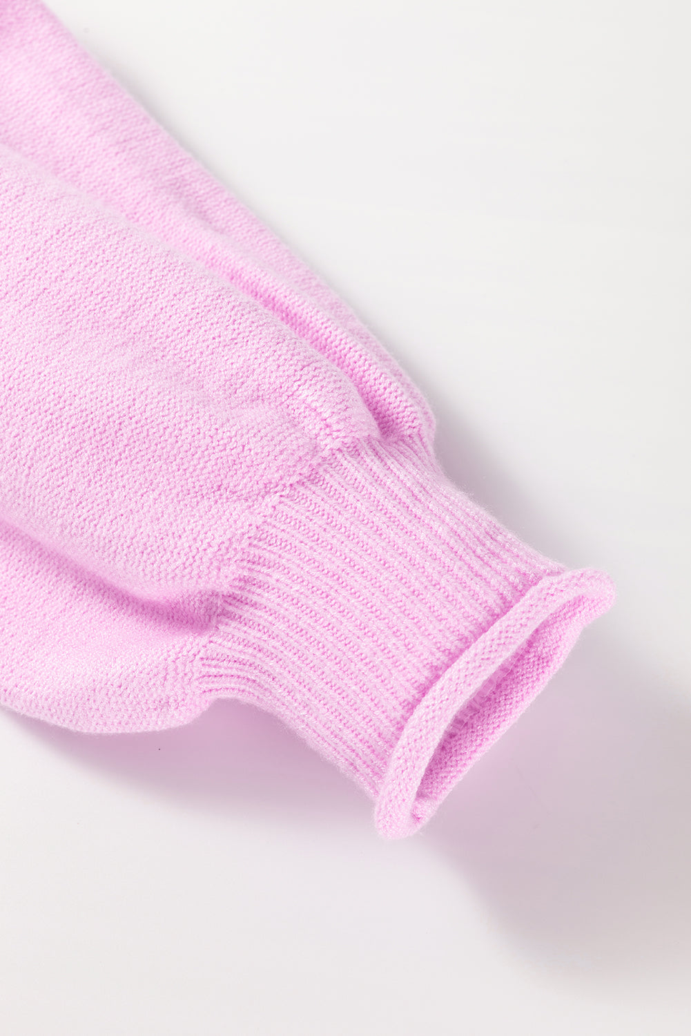 Pink knit sweater sleeve with ribbed cuff and contrast stitching detail.