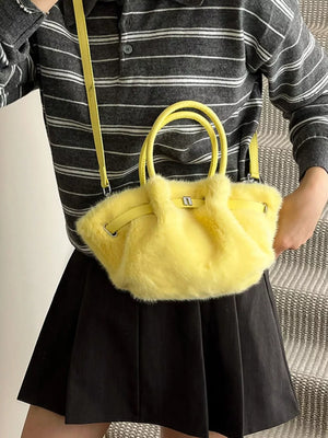 Yellow plush crossbody bag with chic buckle and top handles, styled with a striped shirt and black skirt.