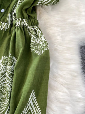 Green wide leg romper with white paisley print, collared, buttoned front, and elastic waist.