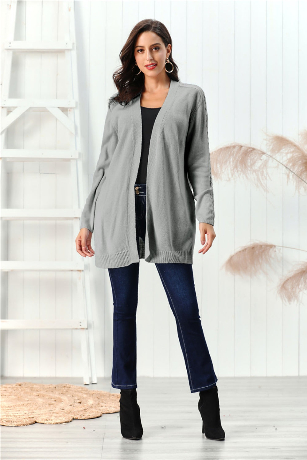 Gray cable knit open front cardigan with braided sleeve detail.