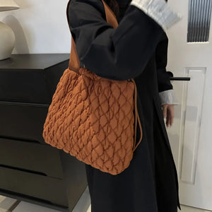 Quilted drawstring carryall bag in Terracotta with diamond stitching and adjustable strap.