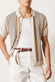 Beige knit polo shirt with vertical stripes and buttoned front, worn over a white tank top.