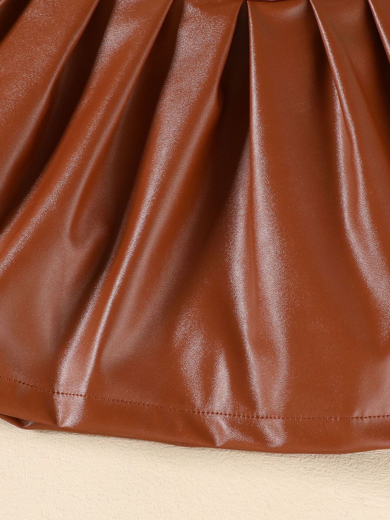 Brown faux leather baby skirt with pleated detail and stitched hem