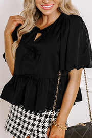 Black peplum blouse with puff sleeves, keyhole neckline and bow details.