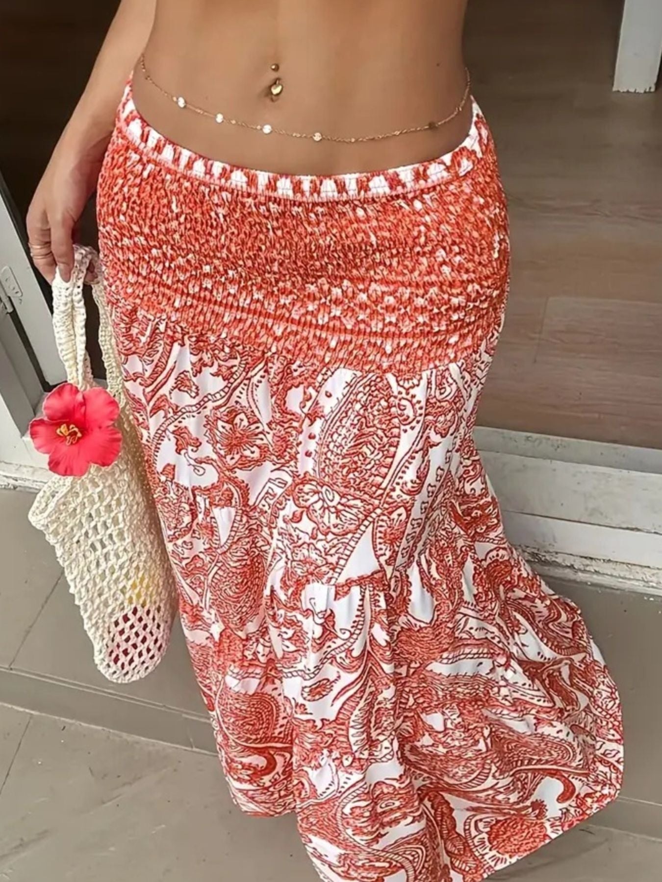 Bohemian maxi skirt in burnt coral paisley print with smocked waist, tiered hem, and flowy silhouette.