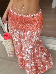 Bohemian maxi skirt in burnt coral paisley print with smocked waist, tiered hem, and flowy silhouette.