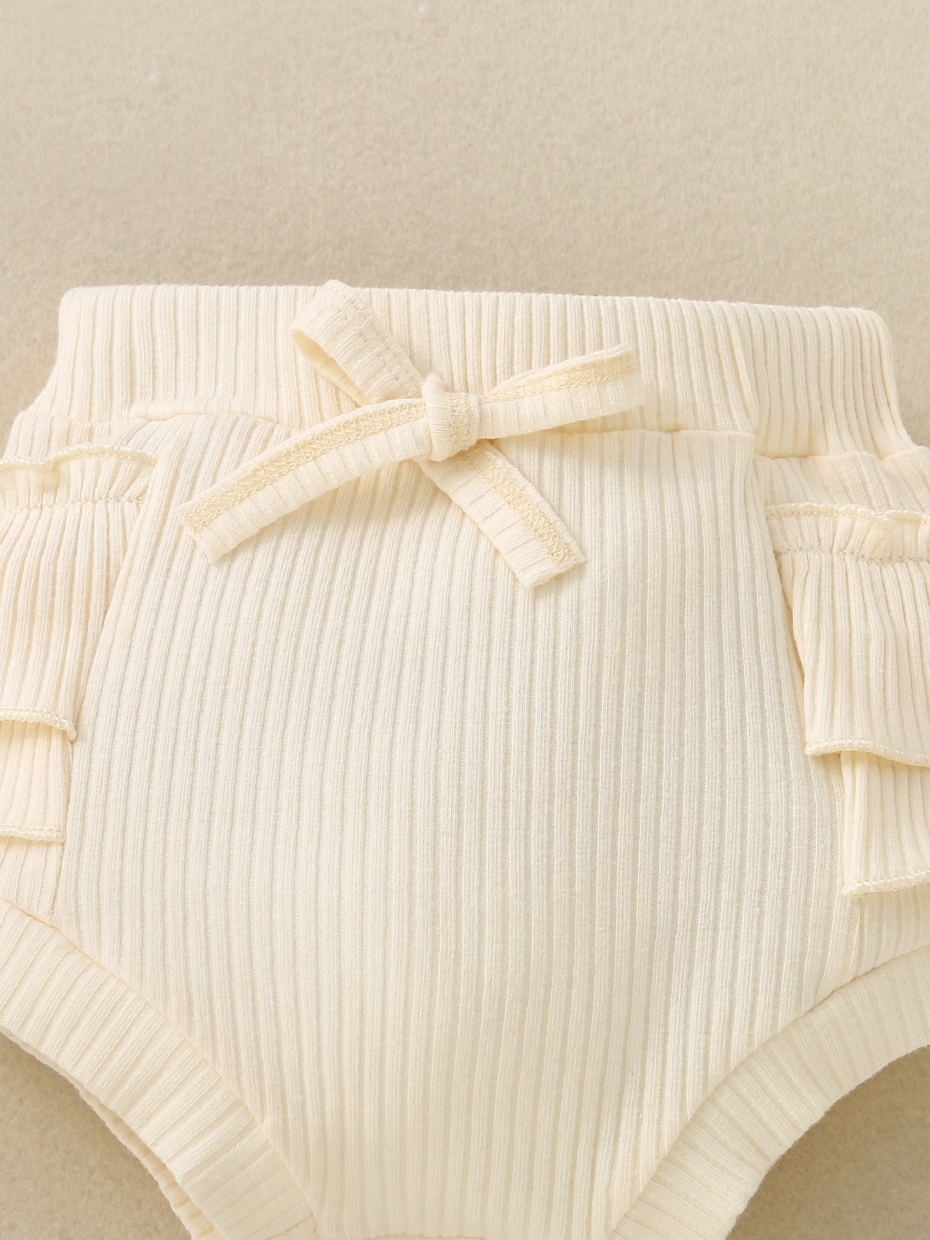 Cream ribbed baby bloomers with ruffle trim and a bow detail