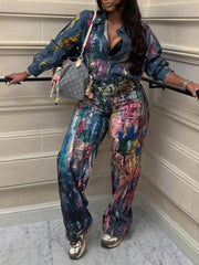 Vibrant artistic denim button-up shirt with colorful paint splatter pattern, long sleeves, and collared neckline.