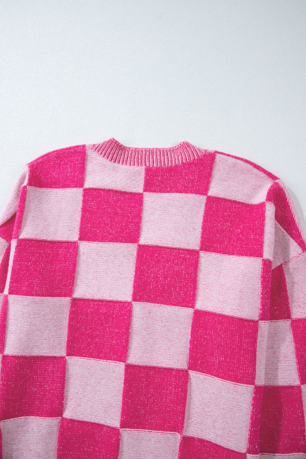 Hot pink checkerboard knit cardigan with crew neck and ribbed trim.
