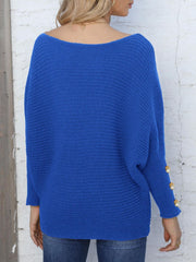 Royal blue batwing knit sweater with boat neck and pearl cuff details.