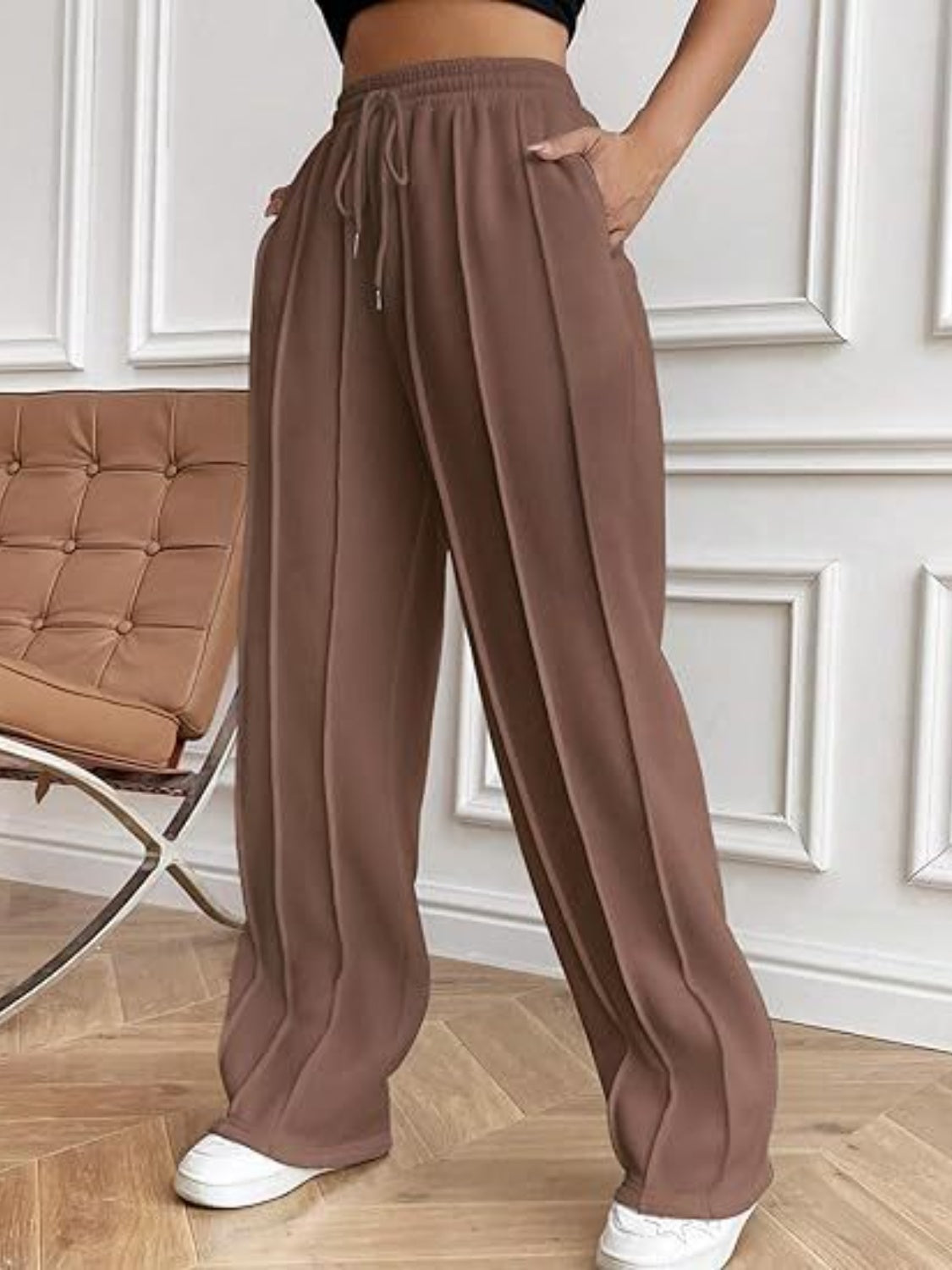 Brown pleated wide-leg lounge trousers with drawstring waist and pockets.