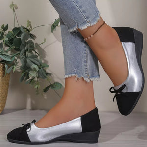 Black and silver slip-on flats with bow detail.