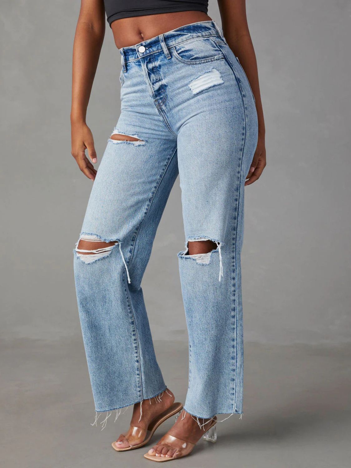 Light wash denim wide leg jeans with distressed knee rips and frayed hem.