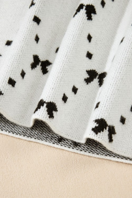 White knit tank sweater with black diamond and bow pattern.
