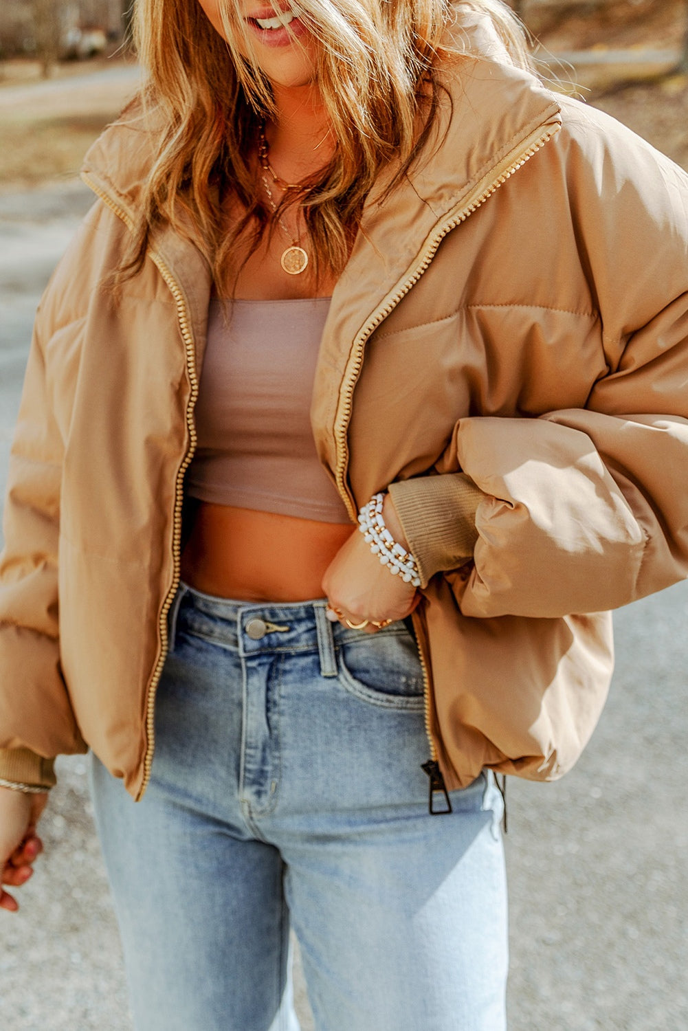 Tan padded crop jacket with stand collar and zip front, styled with jeans.