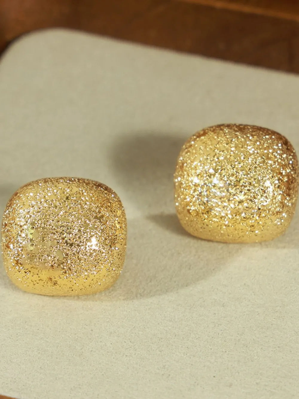 Textured gold cube earrings with glitter detail.