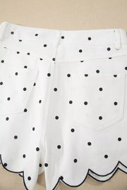 White chino shorts with black polka dots and scalloped hem detail.