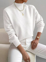 White mock neck knit sweater with dropped shoulders, styled with a gold necklace.