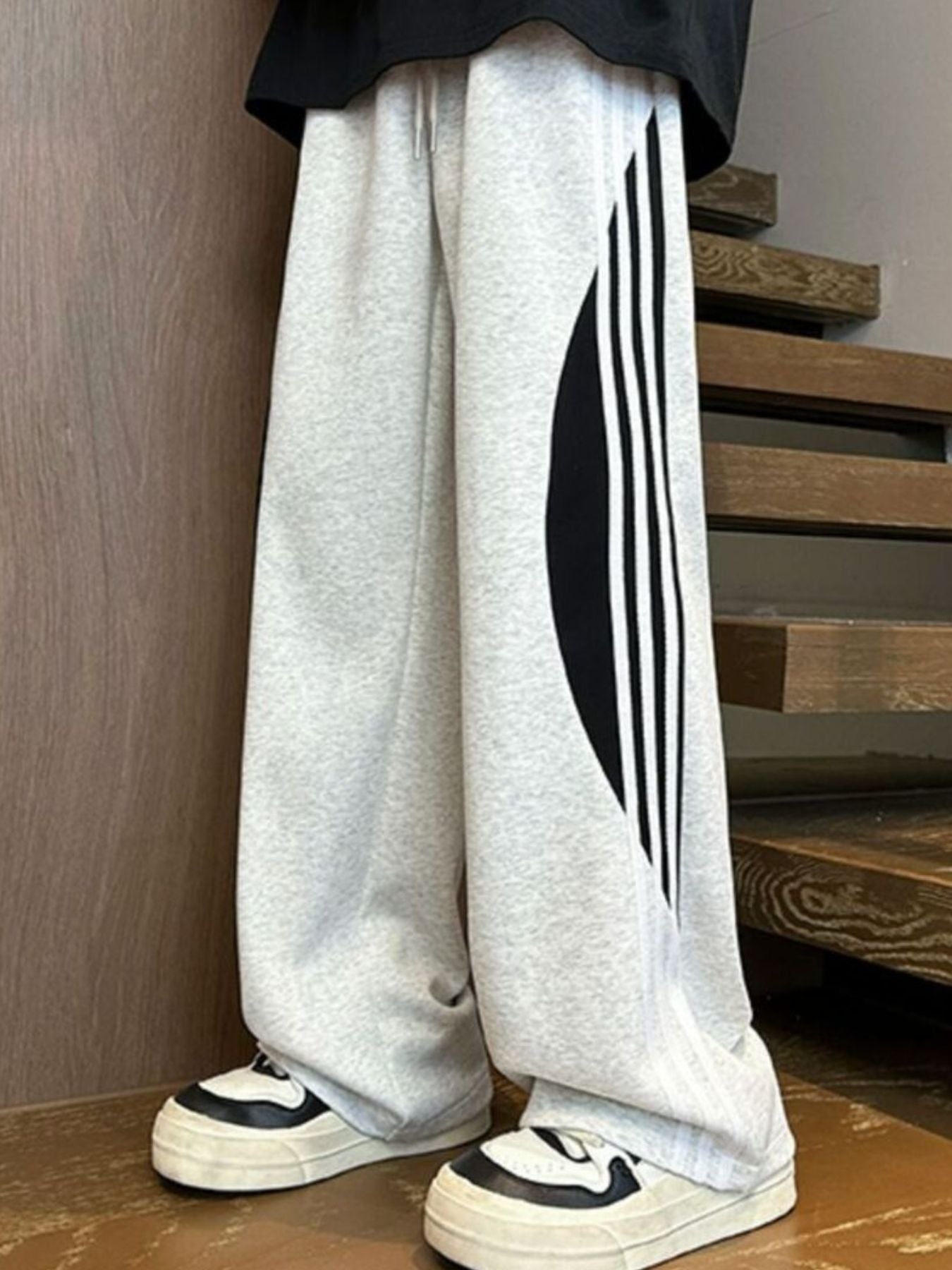 Men's light gray wide leg casual trousers with black side stripe detail and drawstring.