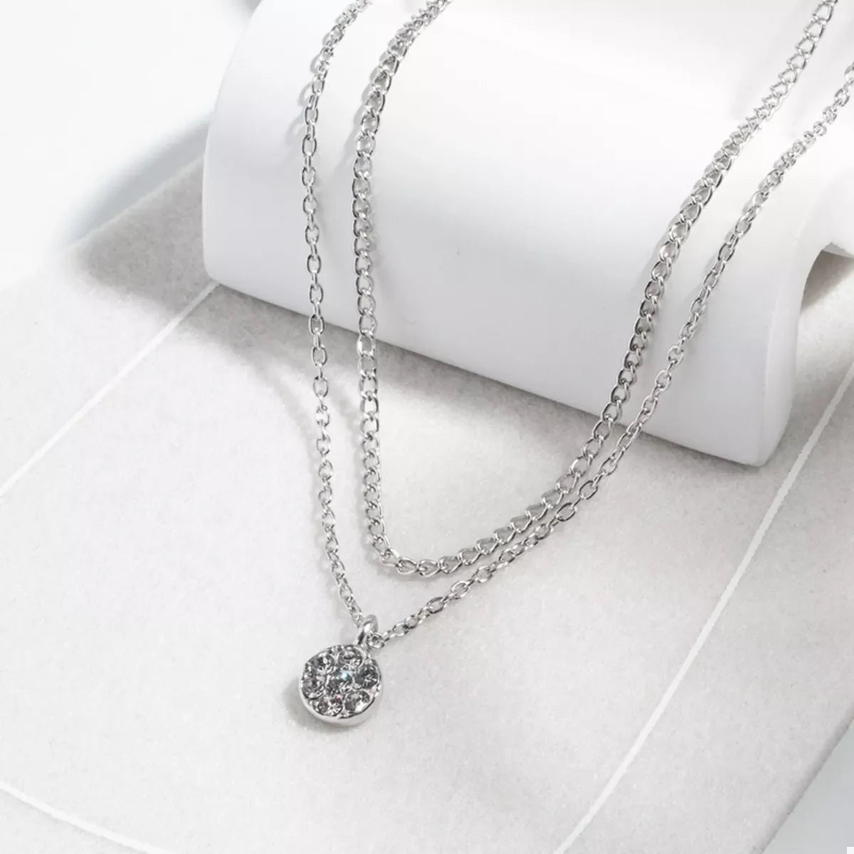 Silver double layered pendant necklace with a round crystal charm.
