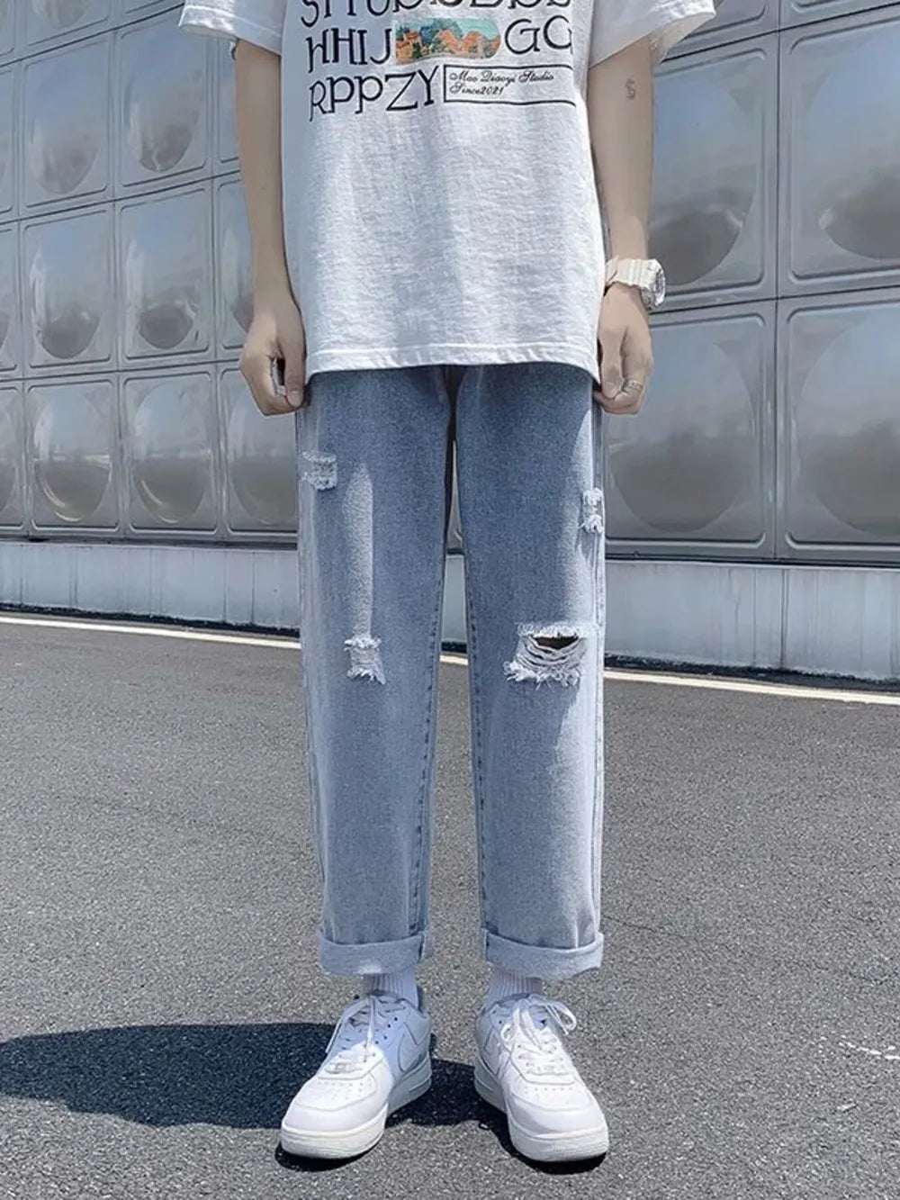 Men's blue distressed relaxed fit jeans with cuffed hem and ripped details.