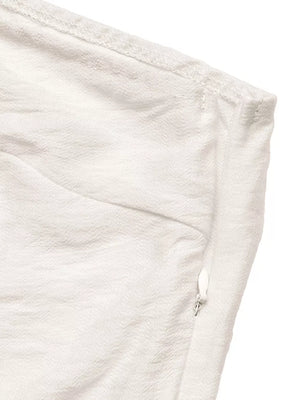Cream one-shoulder top detail with side zipper and textured fabric.