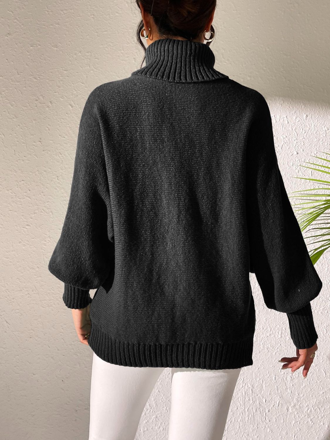 Black knit turtleneck sweater with balloon sleeves and ribbed details.