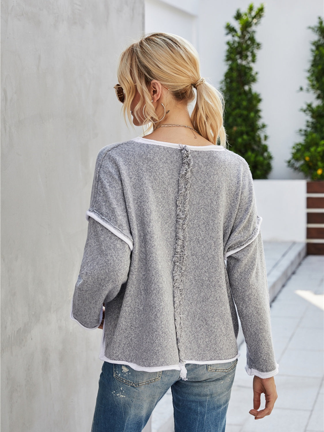 Dark gray knit pullover sweater with white trim and frayed back seam detail.