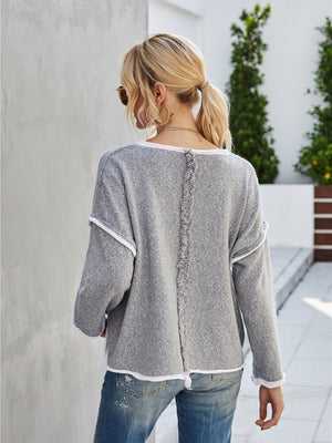 Dark gray knit pullover sweater with white trim and frayed back seam detail.