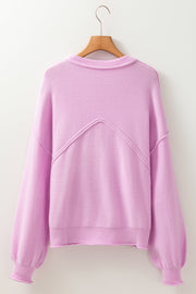 Pink knit sweater with puffed sleeves and contrast stitching detail on the back.
